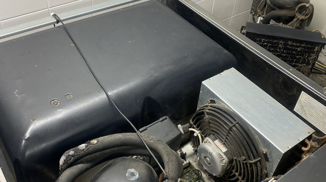 The cooling unit under a refrigerated counter, seen through its front grille