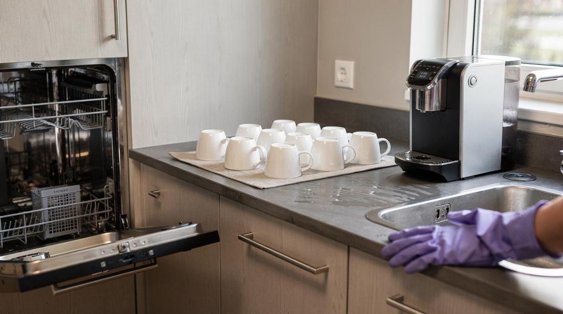 Office kitchenette at the end of a round, dishwasher empty and coffee machine tray being descaled