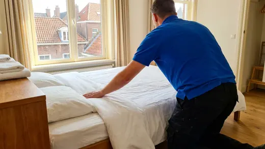 A cleaner making up a guest bed with fresh linen