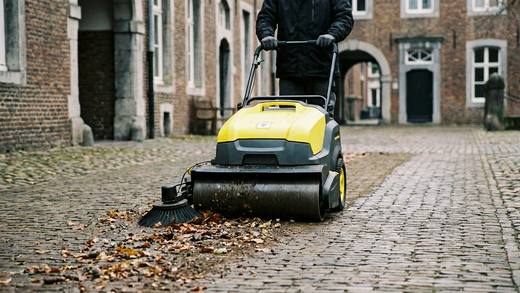 Walk-behind sweeper machine leaving a clean path across the hall floor