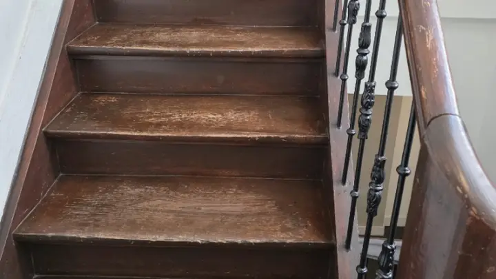 Gelakte houten trap met een ijzeren leuning