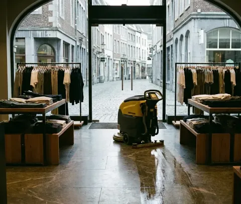 A shop floor being machine-scrubbed before opening, the street outside